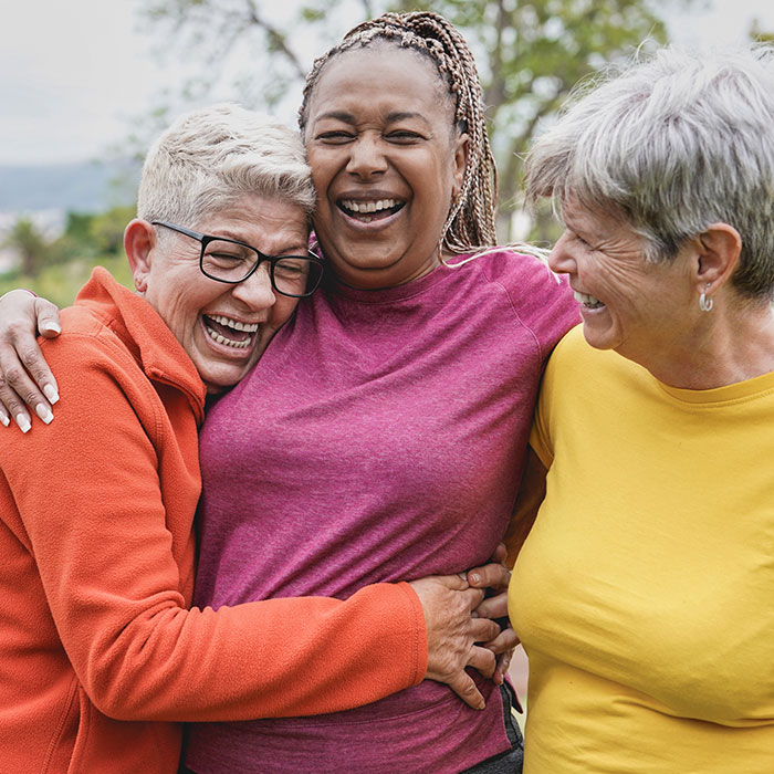 3 women laughing and hugging outside
