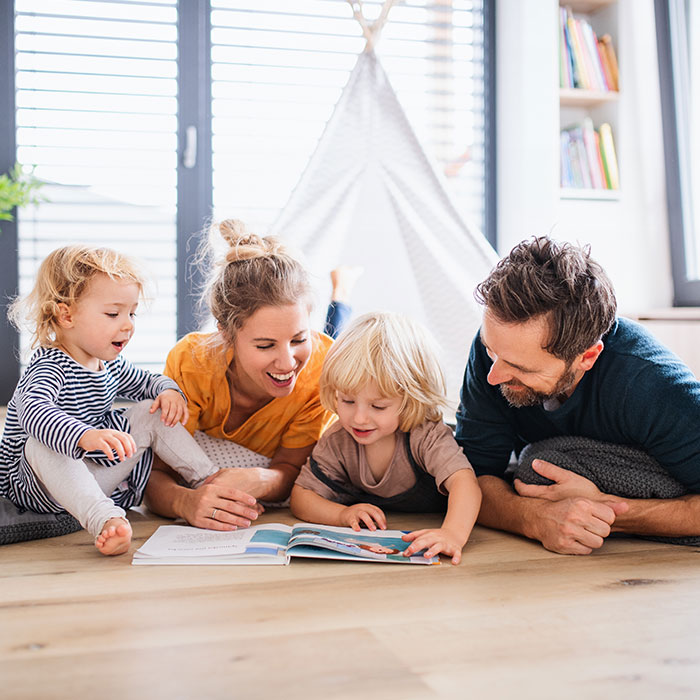 Family with two small children indoors in bedroom reading a book
