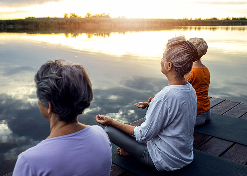 Group of women meditating on a dock