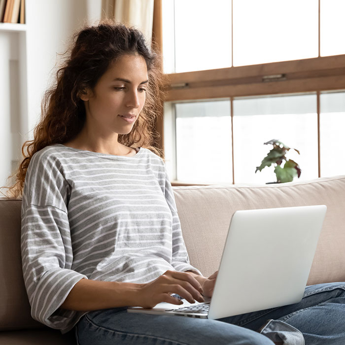 Woman sitting on couch using laptop